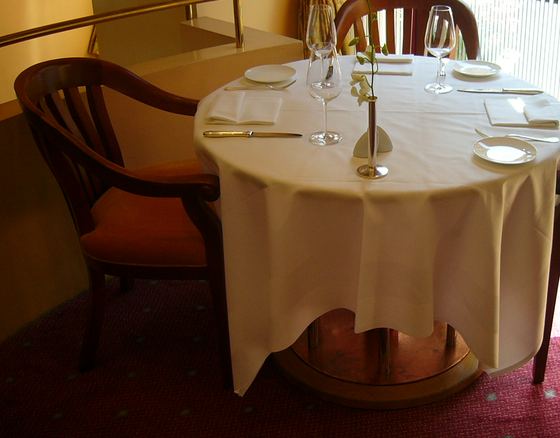 A laid restaurant table for three by a window